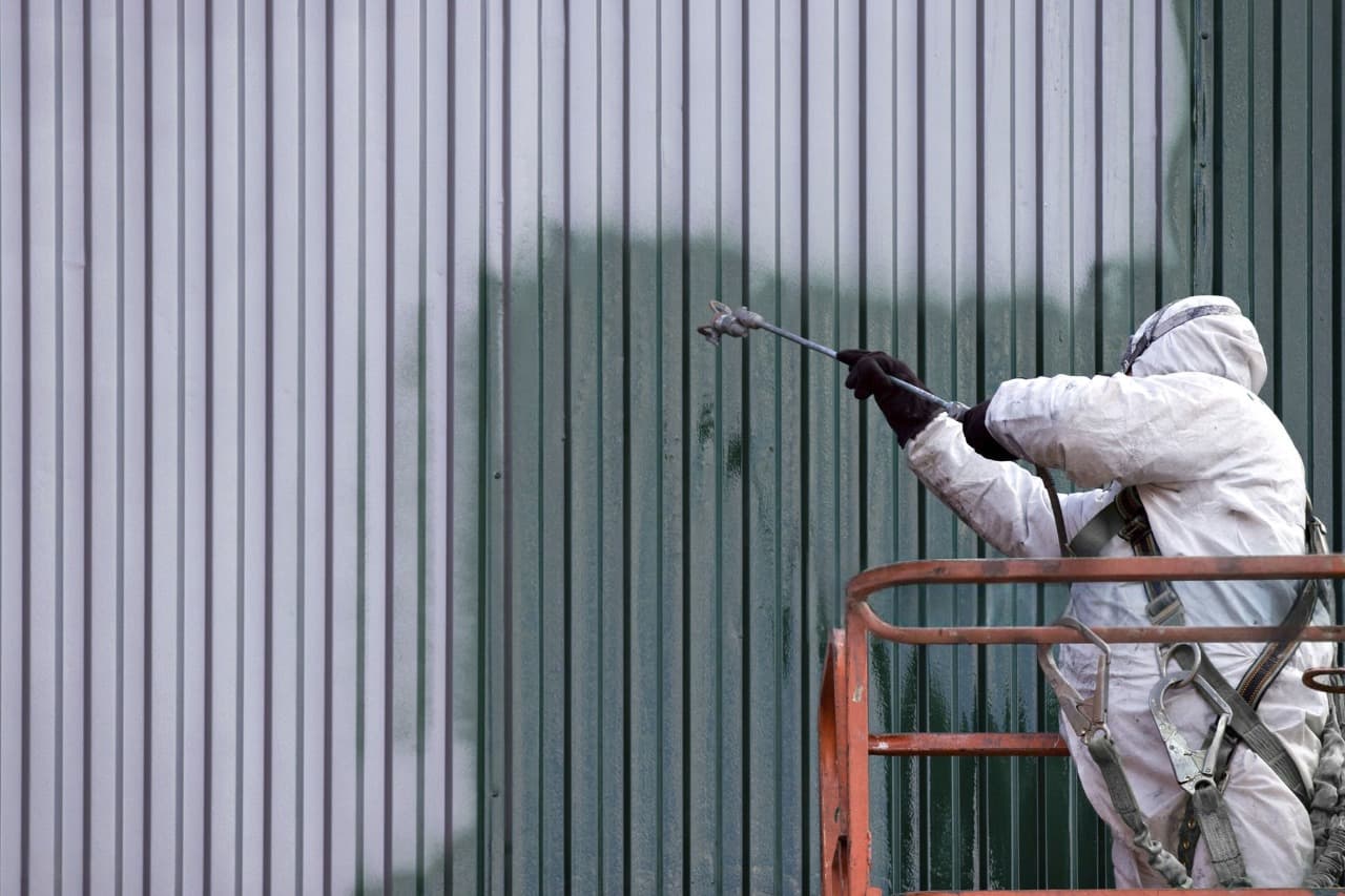 painter spraying the side of a warehouse